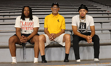 three men sitting together on a bench in an athletic facility
