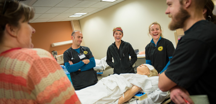 Students in a circle around a training mannequin.