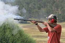 Young man shooting gun in field