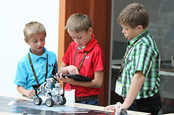 Three young boys programming a robot