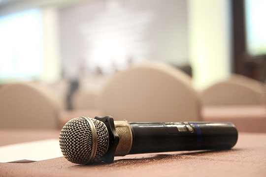 black microphone with a white sheet of paper on a brown table