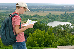 Boy studying a map with a valley and river in the background