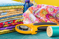Stacked pieces of quilting fabric with rotary cutting tool.