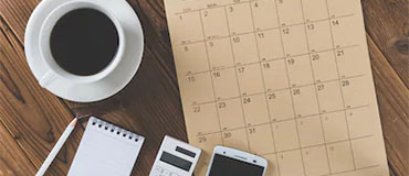 coffee, calendar, pen, phone sitting on a table