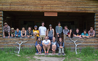 group of people posing on a log porch bracketed by large antlers