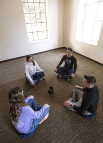 four people sitting in a circle on the floor