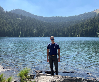 man standing in front of a mountain lake