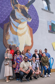 group of people posing in front of a wall mural