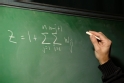 Professor writing a math equation on the chalkboard.
