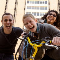 A group of students smile together in front of a building.