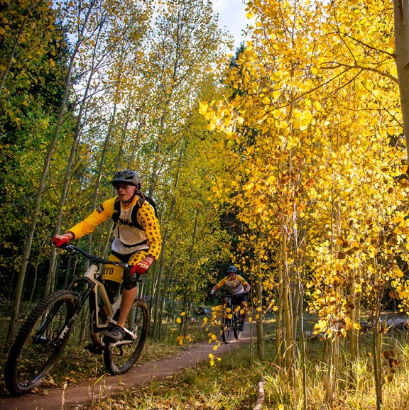A student mountain bikes in the fall.