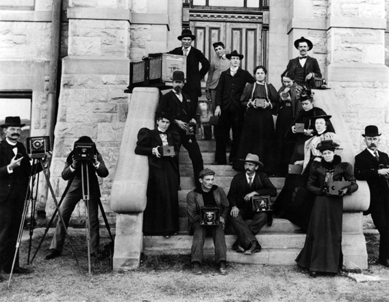 group of people posing outside building holding cameras on a set of stairs