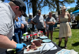 Dr. Cody Gifford slicing meat and cooking demonstration.