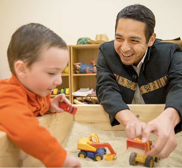 An adult male during a play therapy session with a male child.