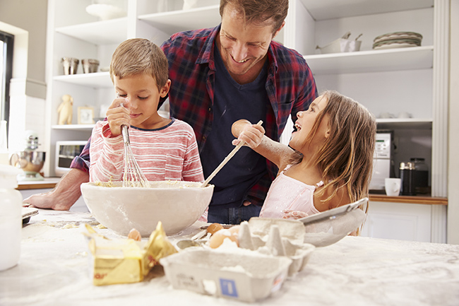 Image of father cooking with two kids