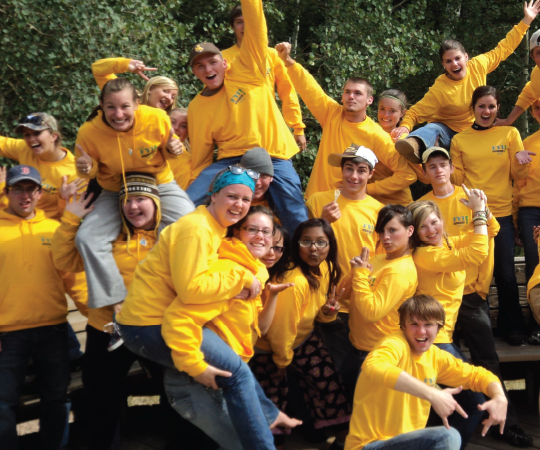 Students in yellow shirts celebrate together.