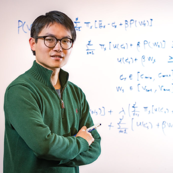 Economic professor in front of equations on a whiteboard