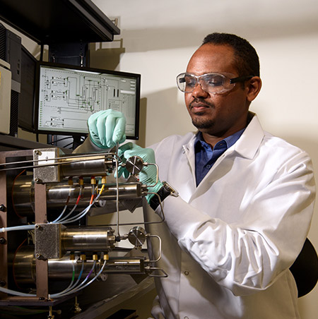 Abdelhalim Mohamed works with a machine at the High Bay Research Facility to study Macro-scale Core Flooding.