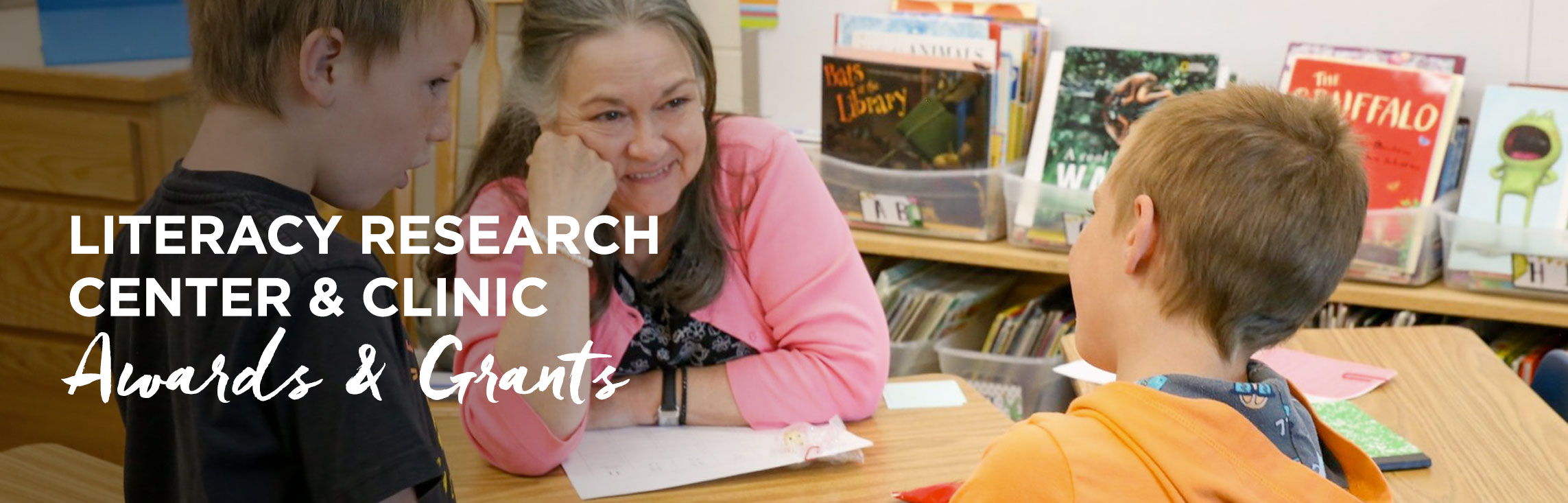 Teacher smiling with students with wording: Literacy Research Center & Clinic Awards & Grants