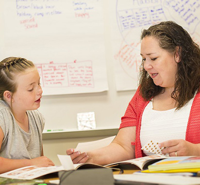A woman tutors a female student in a classroom