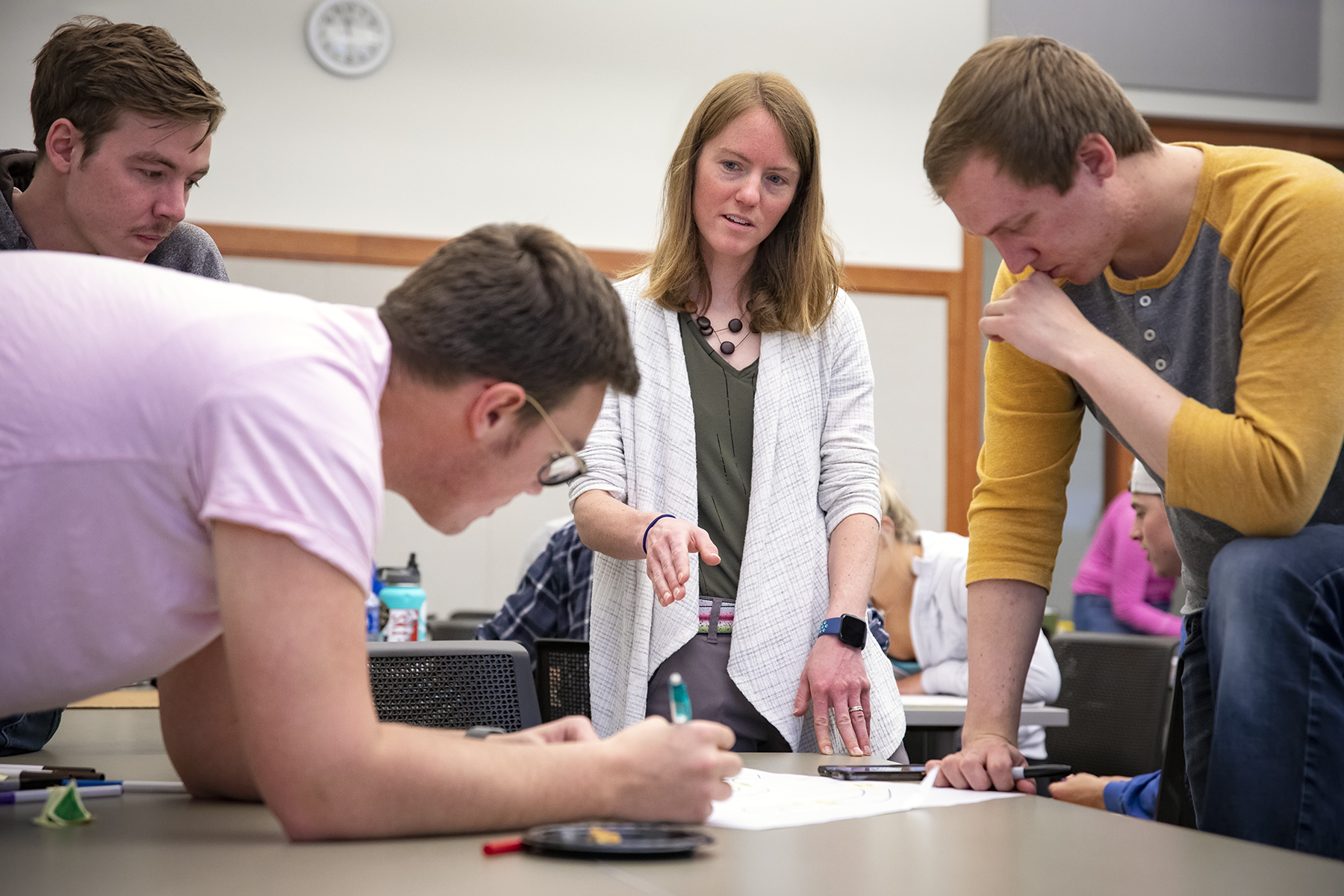 students collaborate in a classroom with guidance from the professor