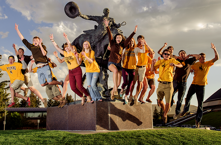 several UW students from the family and consumer sciences program cheering and leaping off of a bucking horse statue