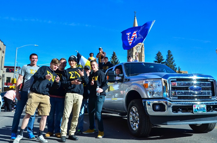 Sigma Nus in homecoming parade wearing letters and waving their flag