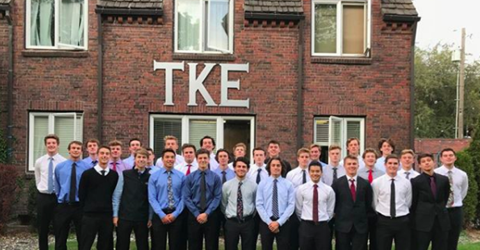 Members of Tau Kappa Epsilon outside of a chapter facility which displays their letters, T K E.