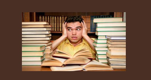 student surrounded by textbooks, overwhelmed expression on face