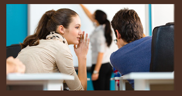student whispers to another student while professor lectures