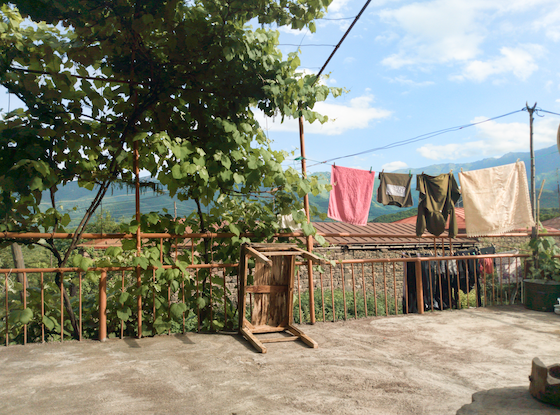 A clothesline, tree, and tilted table on a porch in Armenia