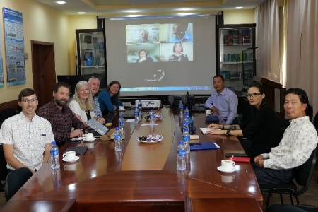 Mongolia conference meeting with 8 participants at a table and five participants on Zoom