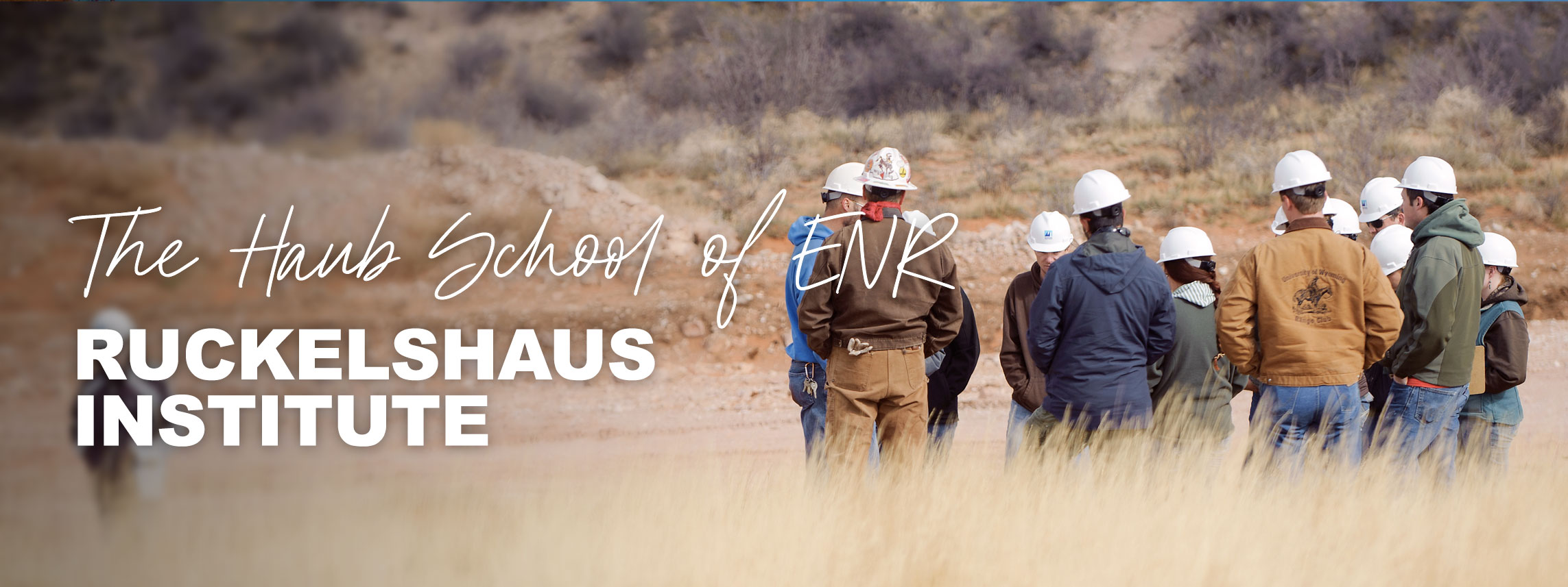 Welcome to the Haub School of ENR Ruckelshaus Institute. People wearing hardhats in field.