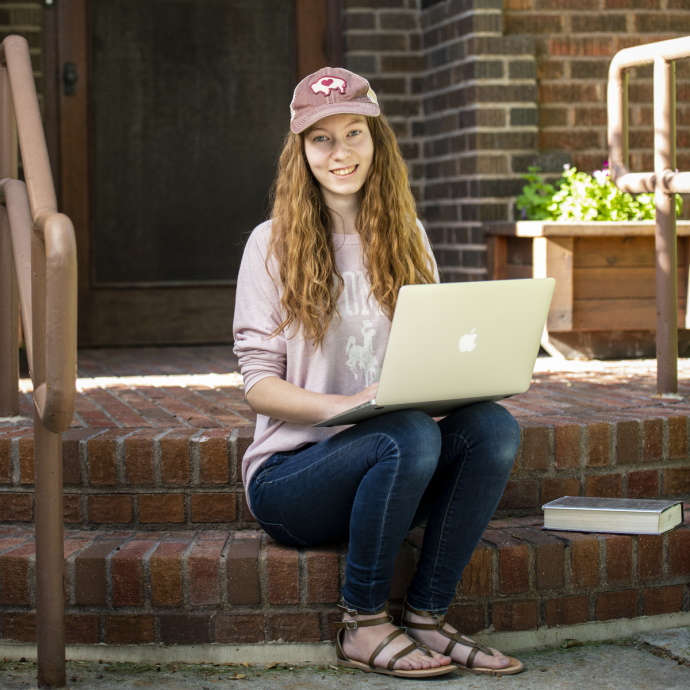 A student sitting outside of Guthrie House with a laptop