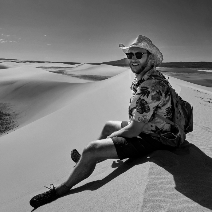 Eric Krszjzaniek sitting on a sand dune