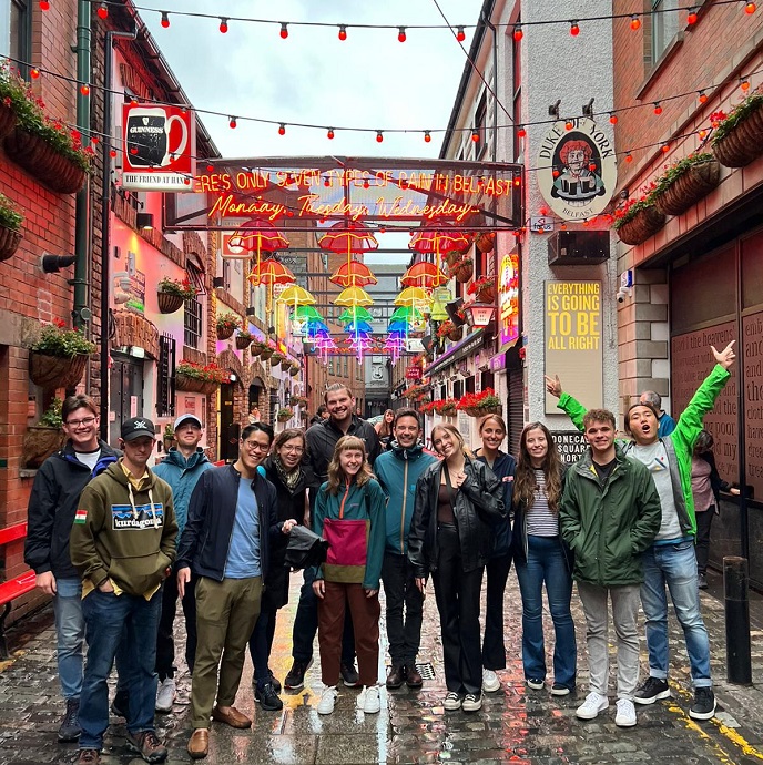 A group of students standing in front of a vibrantly lit street in Belfast