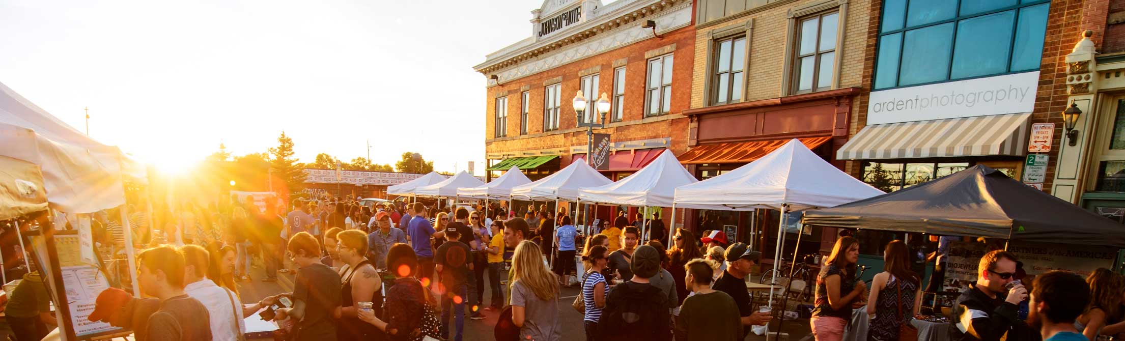 People stand in a crowd at sunset in downtown Laramie.