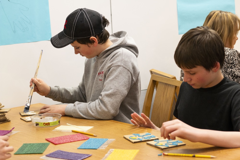 students painting cardboard to build an accessible book