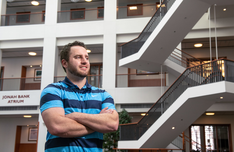 A MBA student standing in the Jonah Bank Atrium