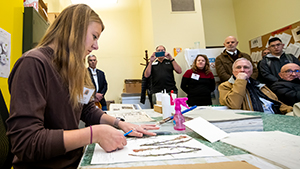 woman mounting specimen in front of group of people