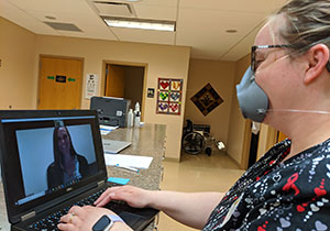 woman in medical setting talking to someone via laptop computer