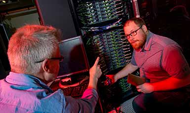 two persons talking next to desktop computer