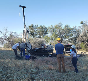people in field with geoprobe
