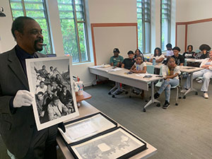 man showing large photos to a classroom
