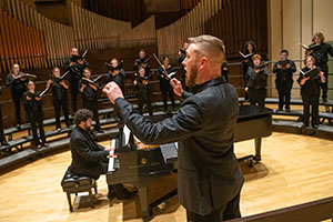man conducting singers on a stage
