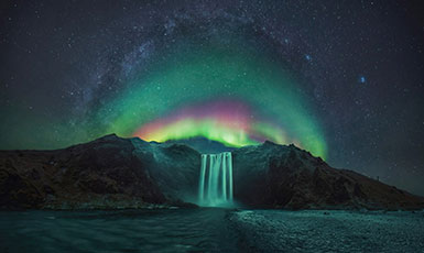 aurora borealis behind a waterfall