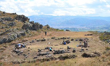 people working at a stone circle dig site in mountains