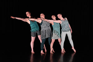 four dancers on stage, gesturing to one side