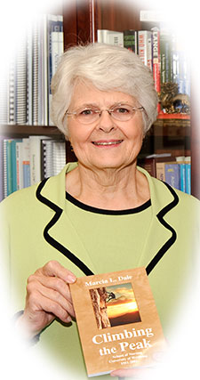 Picture of Marcia Dale posing with her book, "Climbing the Peak"