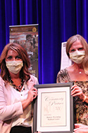 two women, masked for COVID, accept plaque award for their agency